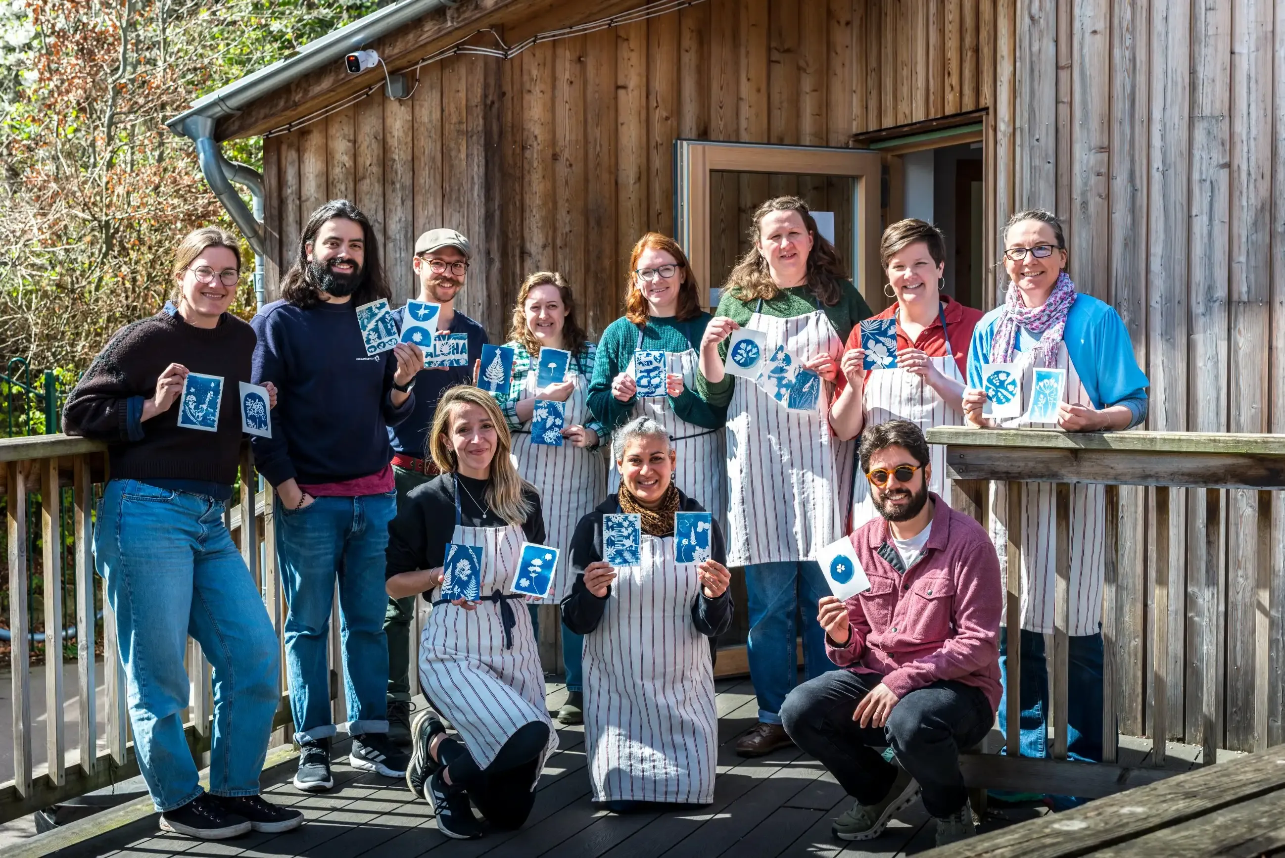 Workshop participants holding up the cyanotype prints they created during a hands-on printmaking session