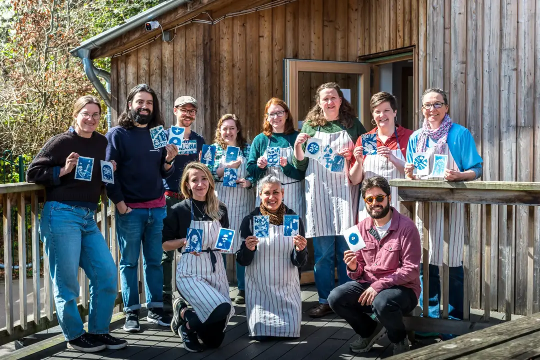Workshop participants holding up the cyanotype prints they created during a hands-on printmaking session