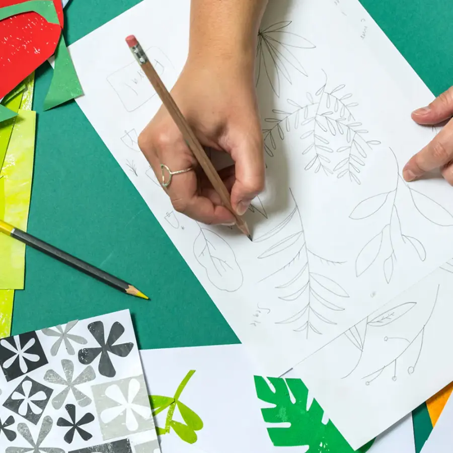 Hand sketching a design on a piece of white paper