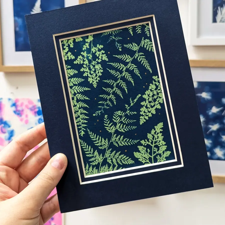 Hand holding a blue and green cyanotype print